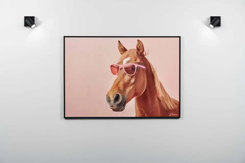 Un tableau encadré représentant un cheval brun portant des lunettes de soleil roses sur un fond rose doux.