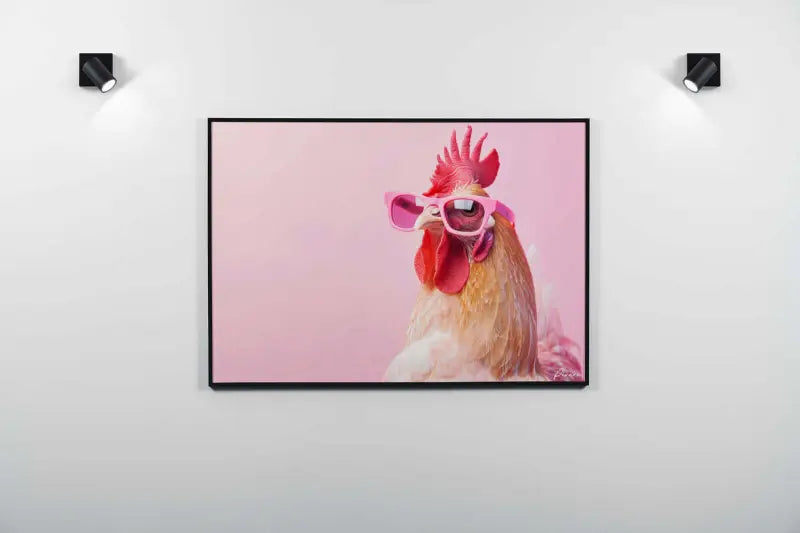Un portrait encadré d’un coq portant des lunettes de soleil roses sur un fond rose doux.