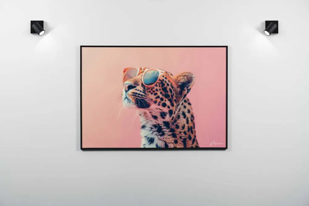 Une impression sur toile encadrée mettant en scène un léopard à la fourrure tachetée distinctive portant des lunettes de soleil élégantes sur un fond rose doux.