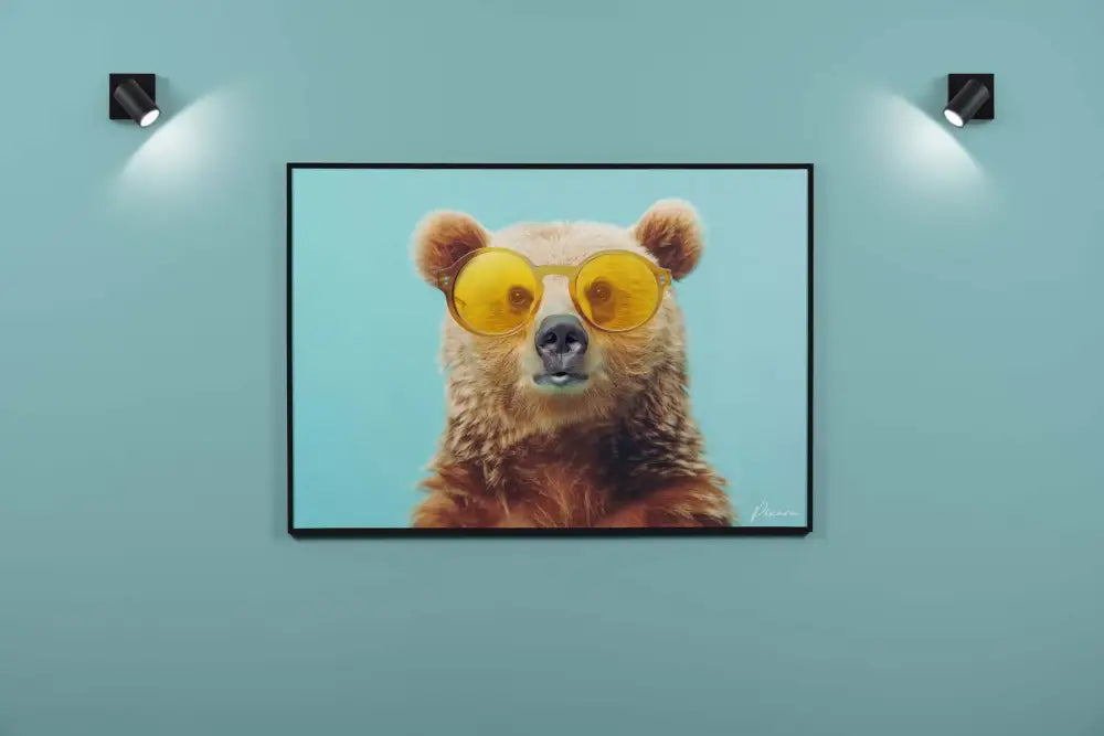 Une impression sur toile encadrée présentant un ours brun portant des lunettes de soleil jaunes surdimensionnées sur un fond bleu clair.