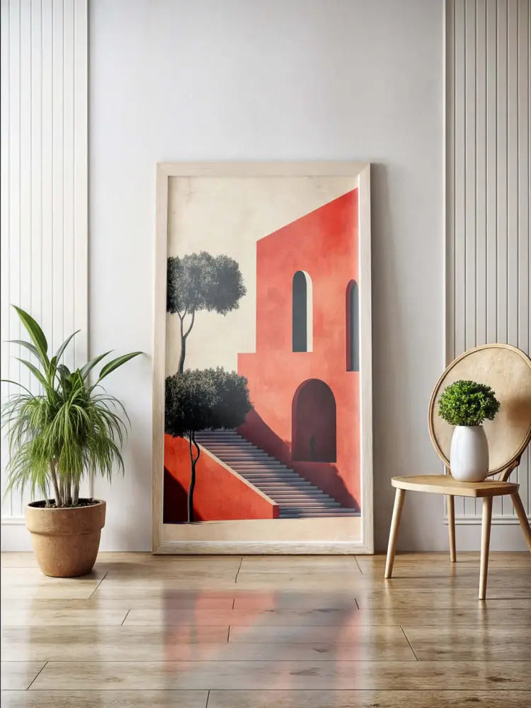 Une œuvre d’art encadrée présentant un bâtiment rouge stylisé avec des fenêtres en arche et des escaliers, flanqué d’arbres verts sombres sur un fond pâle.