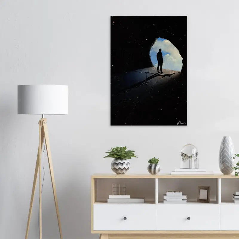 Art sur toile noire représentant une silhouette d’une personne debout à l’entrée d’une grotte, avec des étoiles et le ciel visibles au-delà.