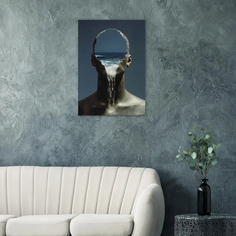 Une impression sur toile surréaliste représentant une figure humaine avec des vagues océaniques s’écoulant de sa tête, montée sur un mur gris texturé.