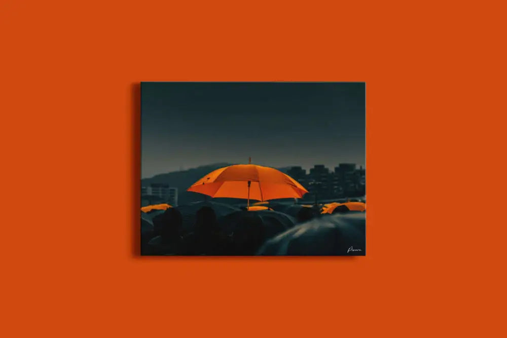 Un parapluie orange vibrant se détache sur un paysage urbain sombre et pluvieux dans cette œuvre d’art encadrée.