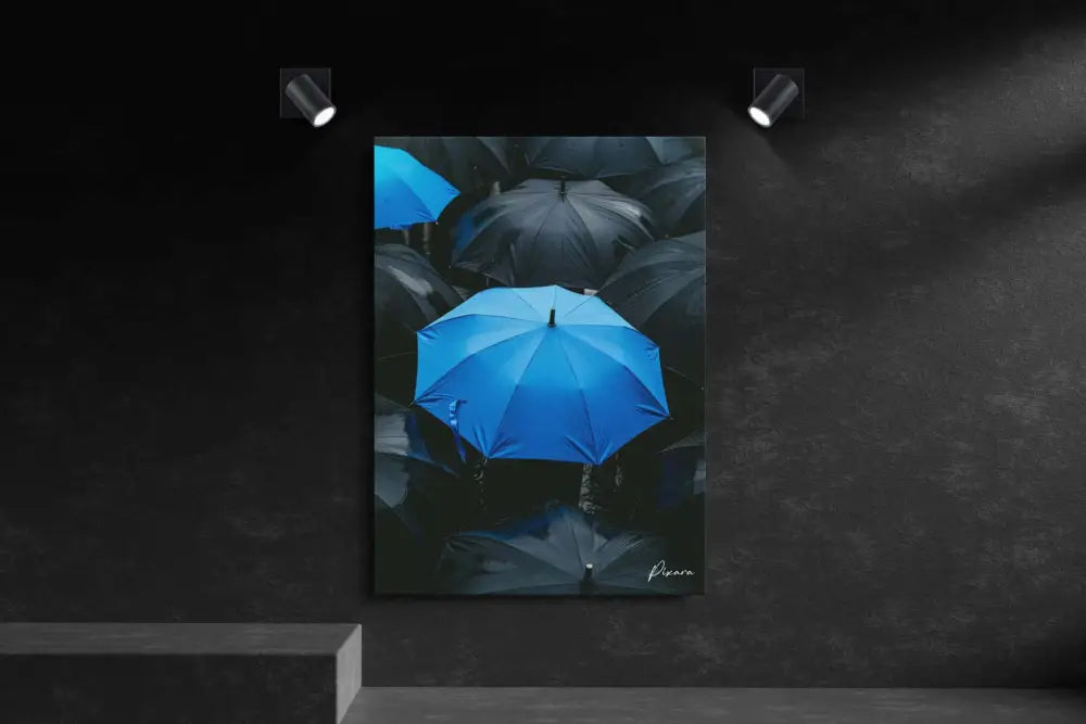 Un parapluie bleu vibrant se détache sur un fond de parapluies sombres et ternes dans cette œuvre d’art encadrée.