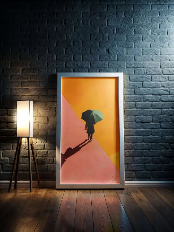 Une œuvre d’art encadrée présentant une silhouette d’une personne tenant un parapluie sur un fond dégradé vibrant orange et rose, enchâssée dans un cadre argenté élégant.