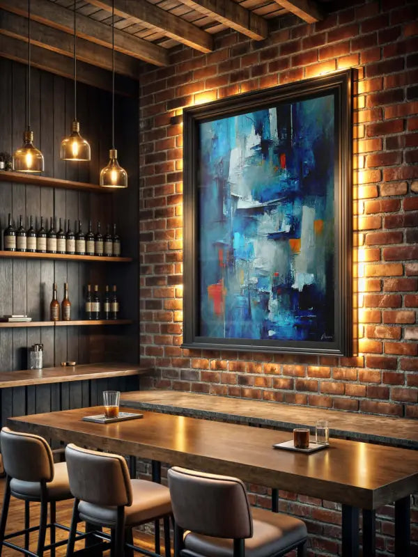 Un tableau abstrait encadré avec des coups de pinceau audacieux en bleu, blanc et orange est accroché sur un mur en brique.