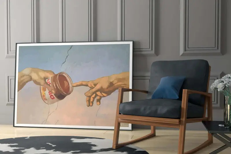 Une impression d’art encadrée dépeignant une parodie de ’la création d’Adam’ avec deux mains se tendant l’une vers l’autre, l’une tenant un pot ouvert de Nutella.