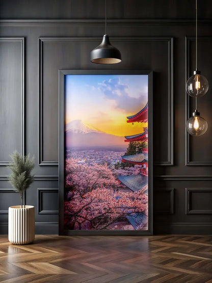 Une photographie encadrée du mont Fuji au coucher du soleil, mettant en vedette des cerisiers en fleurs roses et un temple rouge à l’architecture traditionnelle sur fond de ciel orange vibrant.