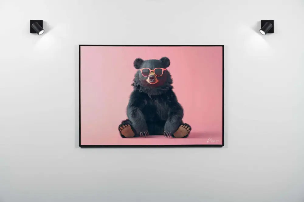 Une œuvre d’art encadrée représentant un ours noir portant des lunettes de soleil stylées à monture orange, sur un fond rose doux.