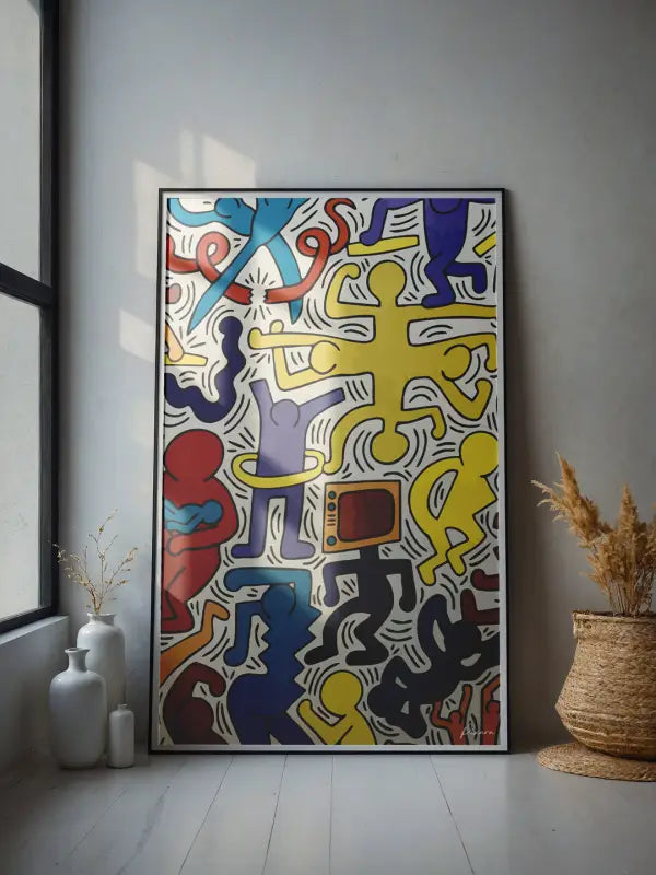 Une œuvre d’art vibrante, encadrée, dans le style de Keith Haring, présentant des figures abstraites audacieuses et colorées en rouge, bleu, jaune et violet sur un fond blanc.