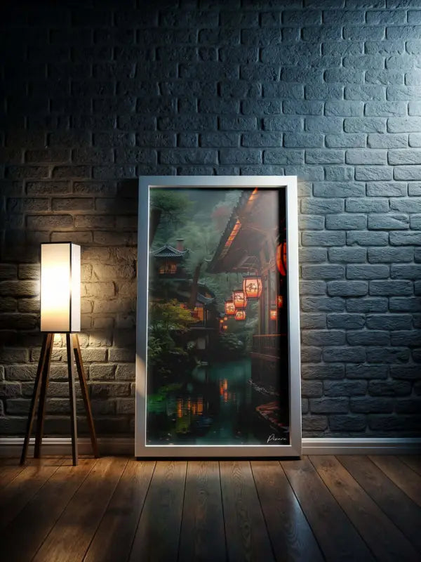 Une œuvre d’art encadrée dépeignant une scène sereine de village japonais avec des lanternes lumineuses et de l’eau réfléchissante, enchâssée dans un cadre argenté élégant.