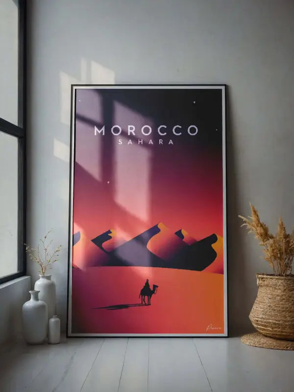 Une affiche encadrée avec un dégradé vibrant de rouge et d’orange représentant le désert du Sahara au Maroc, présentant des silhouettes de dunes et un cavalier de chameau solitaire sur un ciel nocturne étoilé.