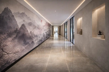 Une grande fresque murale de paysage montagneux monochrome avec de délicates branches d’arbres et des pics brumeux orne le mur gauche d’un couloir moderne.