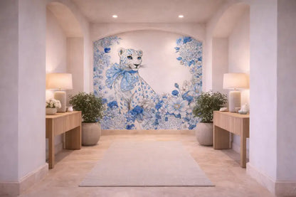 Une frise murale décorative mettant en scène un léopard blanc orné de motifs floraux bleus et d’un nœud assorti, sur un arrière-plan voûté.