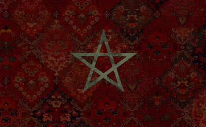 Un emblème de pentagramme vert décoloré centré sur un tapis marocain rouge à motifs riches.