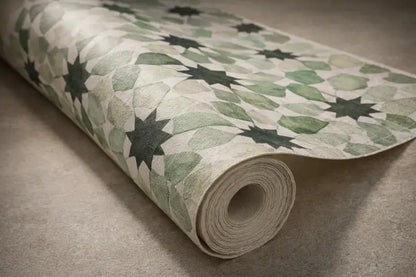 Un rouleau de papier peint arborant un motif de feuilles vertes et de formes d’étoiles sombres sur un fond clair texturé.