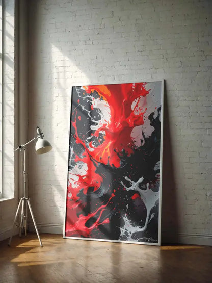Un tableau abstrait audacieux avec des éclaboussures vibrantes de rouge, de noir et de blanc dans un cadre moderne est appuyé contre un mur de briques blanches.