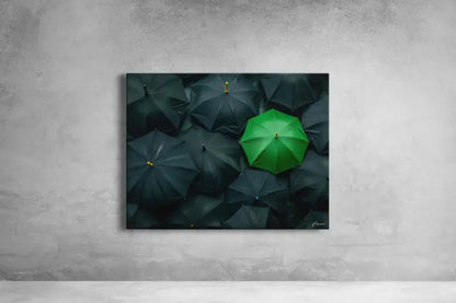 Un parapluie vert vibrant se distingue au milieu d’une mer de parapluies sombres et ternes dans cette impression sur toile encadrée.