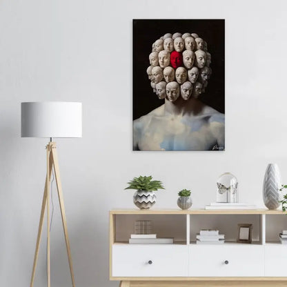 Un impressionnant tirage sur toile présentant une sculpture surréaliste de multiples têtes humaines disposées en motif circulaire autour d’une figure centrale, avec une tête mise en évidence en rouge vif par contraste avec les tons atténués des autres.