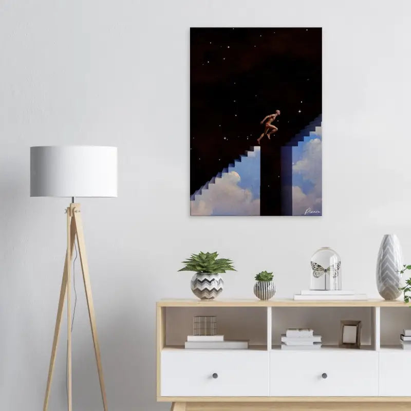 Une impression sur toile rectangulaire représentant une figure nue sautant à travers un escalier pixélisé entre une nuit étoilée et un ciel rempli de nuages, montée sur un mur blanc.