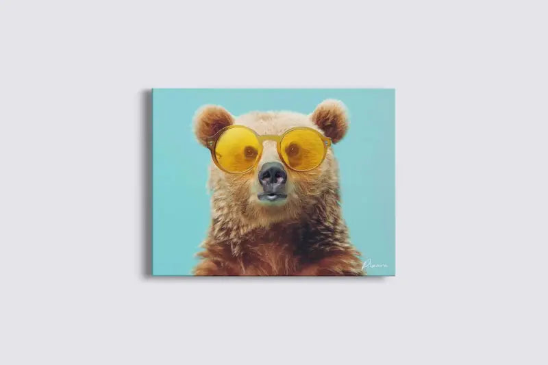 Une impression sur toile représentant un ours brun portant des lunettes de soleil rondes aux verres teintés de jaune sur un fond uni bleu clair.