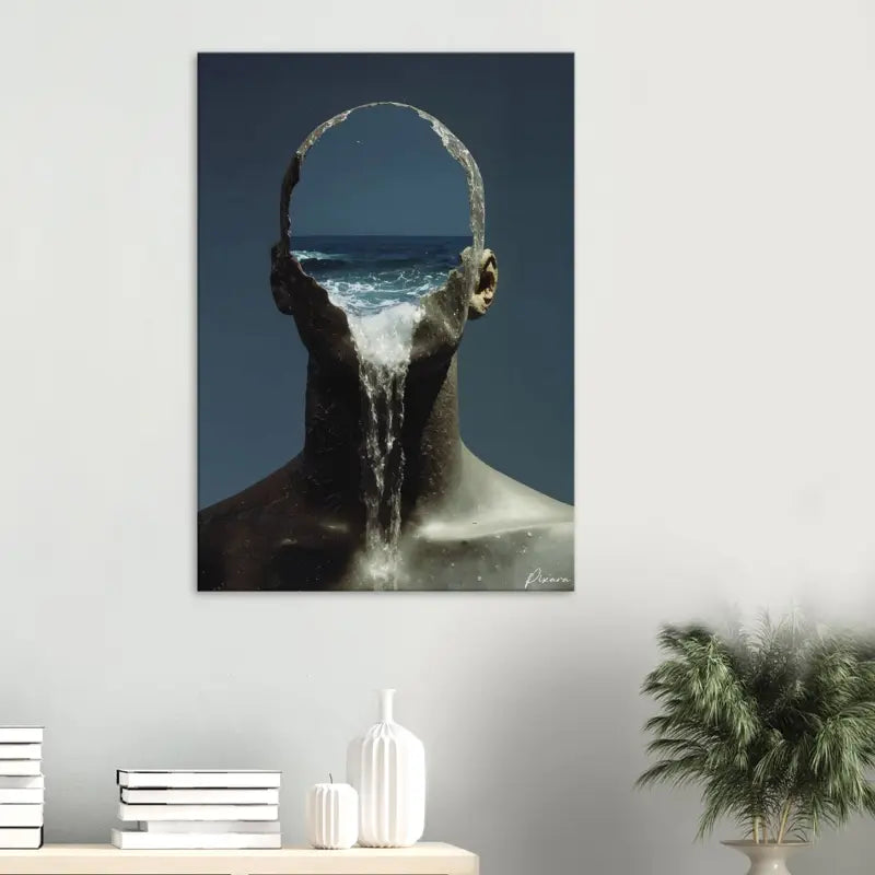 Une impression sur toile surréaliste représentant une sculpture texturée sombre d’une tête humaine avec des vagues océaniques coulant à travers sa forme creuse sur un fond bleu profond.
